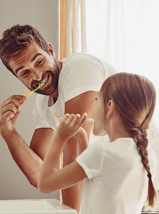 father and daughter brushing their teeth together